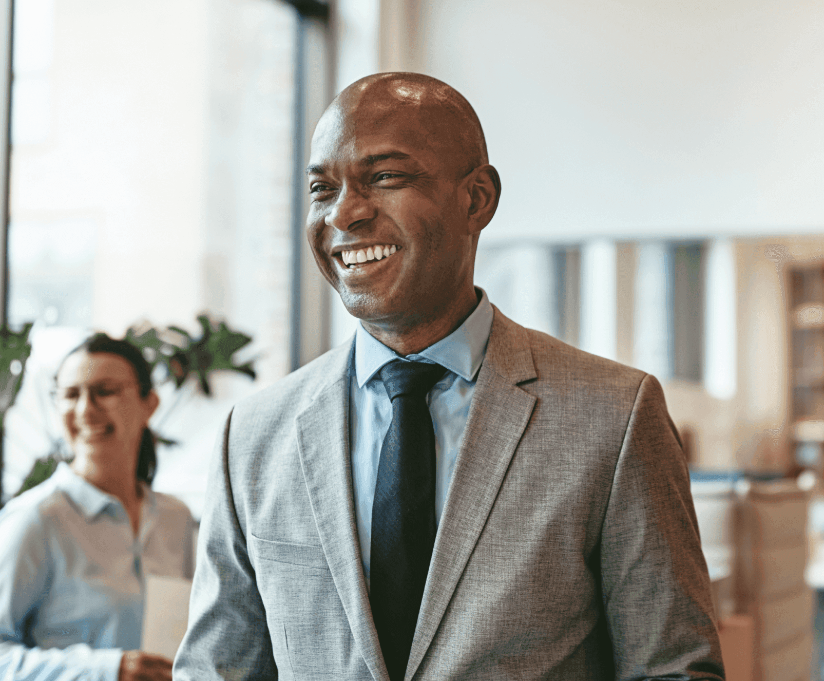 Corporate man smiling in a light gray suite in a modern office setting